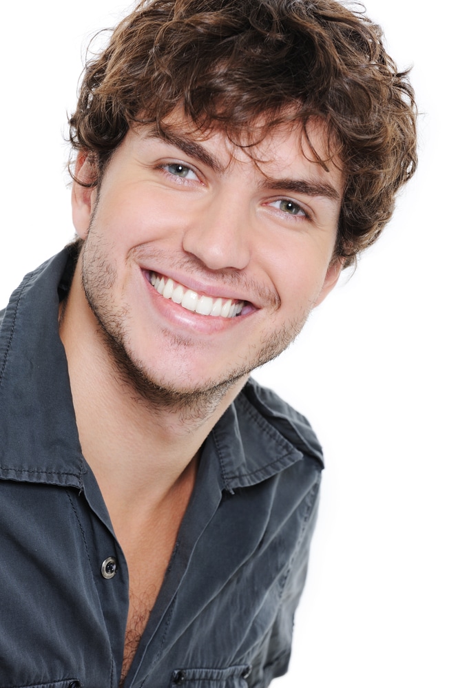 Happy smile and healthy teeth on the face of young man over white