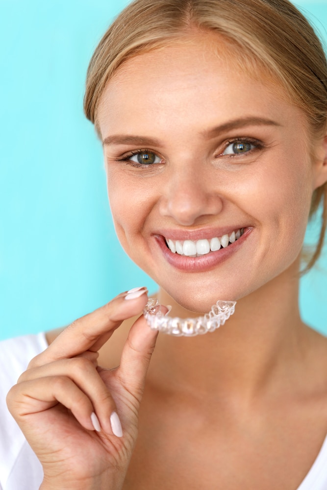 Teeth Whitening. Beautiful Smiling Woman With White Smile, Straight Teeth Using Teeth Whitening Tray. Girl Holding Invisible Braces, Teeth Trainer. Dental Treatment Concept. High Resolution Image